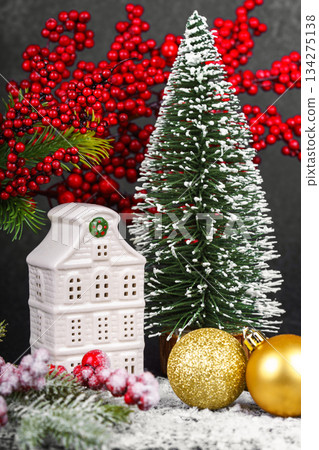 Ceramic Christmas house with pine Tree and winter gold decorations on black background with snow Ceramic Christmas house with pine Tree and winter gold decorations on black background with snow 134275138