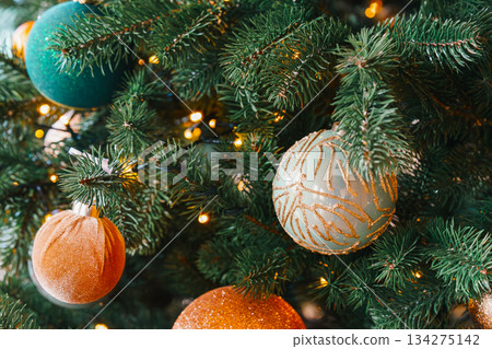 Sparkling christmas tree ornaments in gold and teal on warm holiday lights background Sparkling christmas tree ornaments in gold and teal on warm holiday lights background 134275142