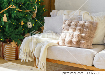 Cozy living room with decorated Christmas tree, warm sofa textiles and wrapped gifts for holidays Cozy living room with decorated Christmas tree, warm sofa textiles and wrapped gifts for holidays 134275143