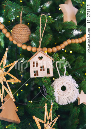 Handmade craft holiday Christmas ornaments on festive green spruce tree, natural wooden rustic decor Handmade craft holiday Christmas ornaments on festive green spruce tree, natural wooden rustic decor 134275145