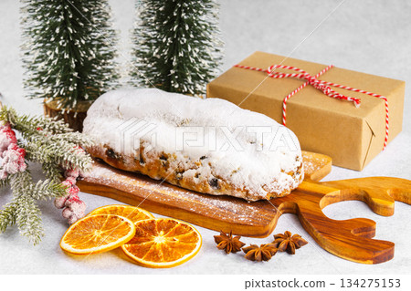 Traditional Christmas Stollen, sweet fruit loaf with sugar icing on wooden board and festive decor Traditional Christmas Stollen, sweet fruit loaf with sugar icing on wooden board and festive decor 134275153