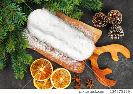 Traditional Christmas Stollen, sweet fruit loaf with sugar icing on wooden board and festive decor Traditional Christmas Stollen, sweet fruit loaf with sugar icing on wooden board and festive decor 134275159