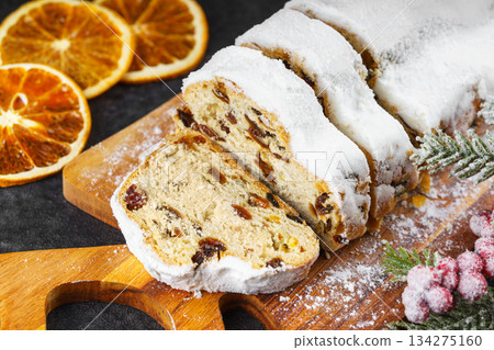 Traditional sliced Christmas stollen loaf with raisins and powdered sugar on wooden cutting board 134275160