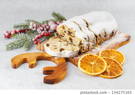 Traditional sliced Christmas stollen loaf with raisins and powdered sugar on wooden cutting board Traditional sliced Christmas stollen loaf with raisins and powdered sugar on wooden cutting board 134275165