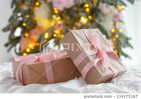 Soft pink Christmas gift boxes with ribbon on blurred holiday festive lights bokeh background 134275167