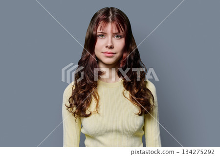 Portrait of smiling teenage girl with curly long hair on gray background 134275292