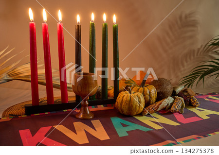 Kwanzaa Celebration Setup. Seven candles signify Kwanzaa with decorative gourds, corn, and vibrant tablecloth. Kwanzaa Celebration Setup. Seven candles signify Kwanzaa with decorative gourds, corn, and vibrant tablecloth. 134275378