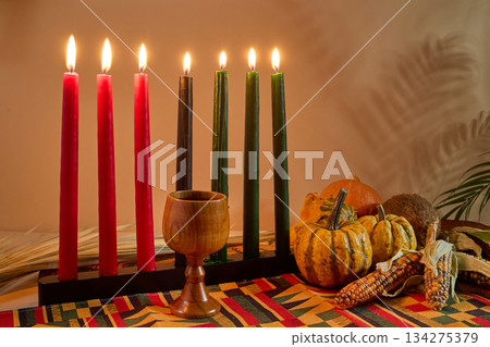 Kwanzaa Celebration Display. A traditional Kwanzaa setup with candles, fruits, and a wooden cup Kwanzaa Celebration Display. A traditional Kwanzaa setup with candles, fruits, and a wooden cup 134275379
