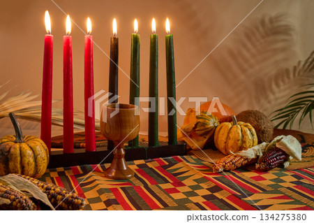 Kwanzaa Celebration Display. A traditional Kwanzaa setup with candles, fruits, and a wooden cup 134275380