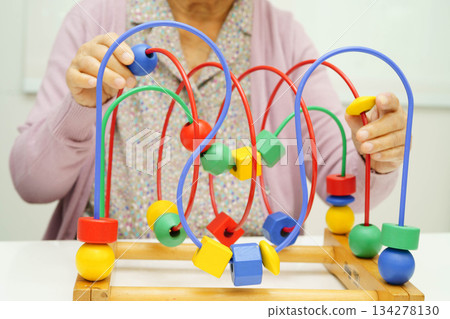 Asian elderly woman playing enhancing skill board game. 134278130