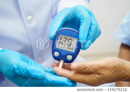 Asian doctor using digital glucose meter for check sample blood sugar level to treatment diabetes. 134278218