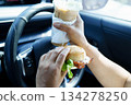 Asian woman driver hold and eat hamburger food in car. 134278250