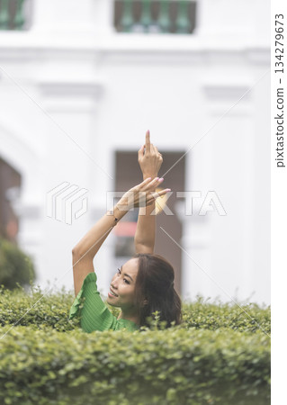 Asian model in green dress poses gracefully in city park, nature concept Asian model in green dress poses gracefully in city park, nature concept 134279673