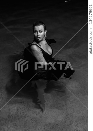 A sexy girl in a black swimsuit poses at night by the pool at a party. A sexy girl in a black swimsuit poses at night by the pool at a party. 134279691