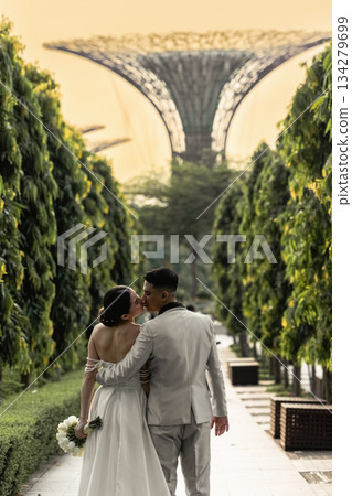 A beautiful wedding couple is kissing with Gardens by the Bay in Singapore. A beautiful wedding couple is kissing with Gardens by the Bay in Singapore. 134279699