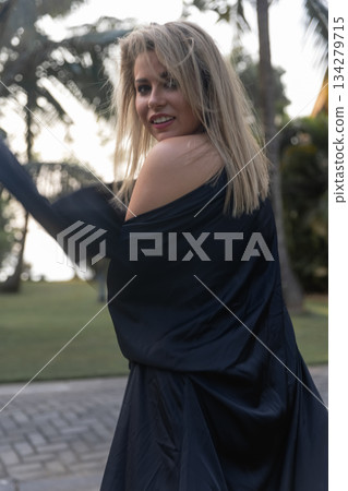 A beautiful Caucasian blonde is walking in nature wearing a black hat. The luxury of the territory of an expensive hotel. A beautiful Caucasian blonde is walking in nature wearing a black hat. The luxury of the territory of an expensive hotel. 134279715