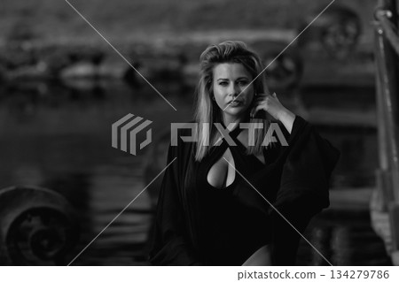 A beautiful Caucasian blonde is walking in nature wearing a black hat.  134279786