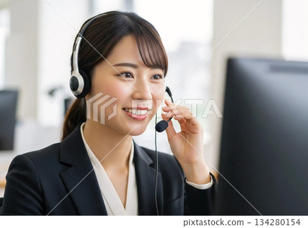 A business scene where a smiling female staff member responds at a call center 134280154