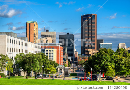 Downtown Saint Paul skyline rises beyond the green lawns of the Minnesota State Capitol Mall. View features Wells Fargo Place and government buildings under a blue summer sky 134280498