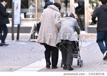 日本橫濱城市景觀，十二月…老化社會。一位老婦人使用四輪助行器，一位女性護理員在一旁攙扶… 134280536