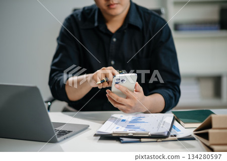 Businessman sitting front tablet ,laptop computer with financial graphs and statistics on monitor 134280597