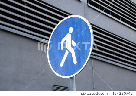 Minimalist urban scenery with prominent blue pedestrian sign emphasizing safety passage 134280742