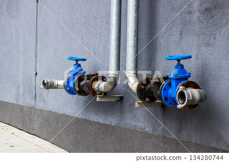 Industrial exterior scene featuring aged water valves and weathered infrastructure components Industrial exterior scene featuring aged water valves and weathered infrastructure components 134280744