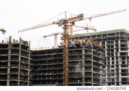 Construction rising under cloudy skies, Building site bustling with cranes and workers Construction rising under cloudy skies, Building site bustling with cranes and workers 134280749