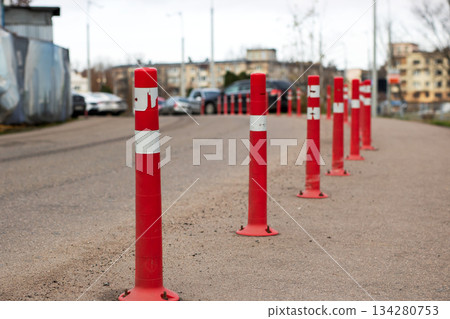 Red posts guide, Colorful safety indicators set along pathway leading towards distant cityscape Red posts guide, Colorful safety indicators set along pathway leading towards distant cityscape 134280753