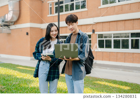 Two smart young Asian college students focusing on his school project, looking at laptop and tablet, discussing and working together 134280831