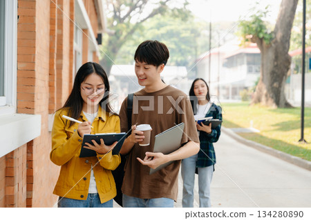 Two smart young Asian college students focusing on his school project, looking at laptop and tablet, discussing and working together Two smart young Asian college students focusing on his school project, looking at laptop and tablet, discussing and working together 134280890