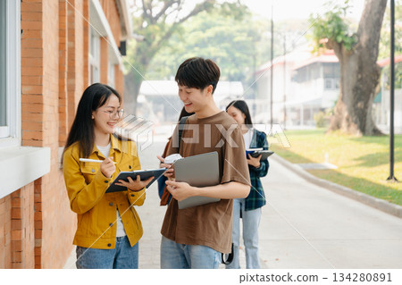 Two smart young Asian college students focusing on his school project, looking at laptop and tablet, discussing and working together Two smart young Asian college students focusing on his school project, looking at laptop and tablet, discussing and working together 134280891