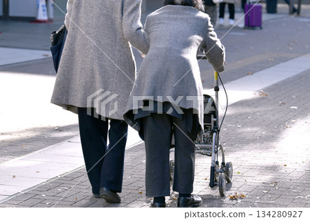 Yokohama cityscape in Japan. December... Aging society. An elderly woman using a four-wheeled walker. A female caregiver supports her... 134280927