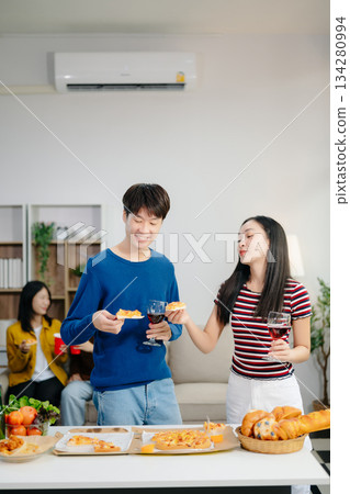 Young Asian friend having, enjoy evening party together at home. Attractive young man and woman having fun, eating food, celebrate at home Young Asian friend having, enjoy evening party together at home. Attractive young man and woman having fun, eating food, celebrate at home 134280994