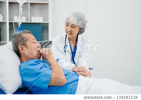 Asian doctor in white suit take notes while discussing and Asian elderly, man patient who lying on bed with receiving saline solution 134281116