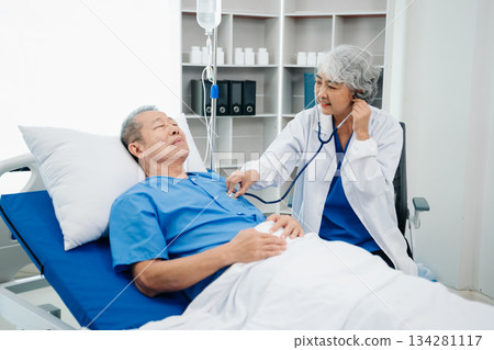 Asian doctor in white suit take notes while discussing and Asian elderly, man patient who lying on bed with receiving saline solution 134281117