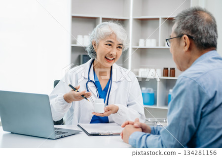 Asian female hands touching senior male hand Helping hands holding bottle with pills in hands, reading instruction take care 134281156