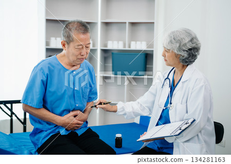 Asian doctor in white suit take notes while discussing and Asian elderly, man patient who lying on bed with receiving saline solution 134281163