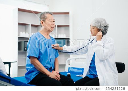 Asian doctor in white suit take notes while discussing and Asian elderly, man patient who lying on bed with receiving saline solution 134281226
