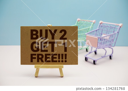 Buy 2 Get 1 Free!!! text on paper card and trolley shopping cart on pastel background 134281768