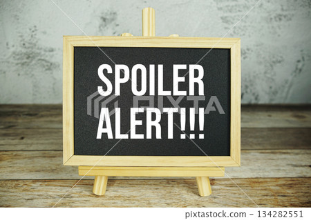 wooden easel displays a blackboard with the bold white text "Spoiler Alert!!!" set against a rustic wooden surface and textured gray wall background wooden easel displays a blackboard with the bold white text "Spoiler Alert!!!" set against a rustic wooden surface and textured gray wall background 134282551