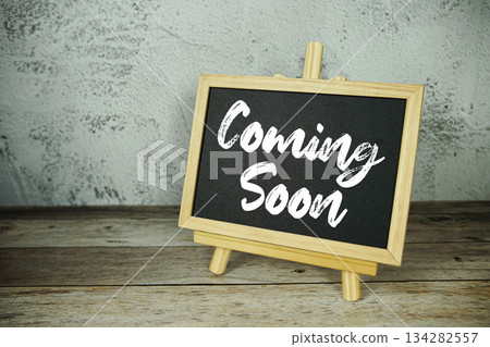 wooden easel displays a blackboard with the bold white text "Coming Soon" set against a rustic wooden surface and textured gray wall background wooden easel displays a blackboard with the bold white text "Coming Soon" set against a rustic wooden surface and textured gray wall background 134282557