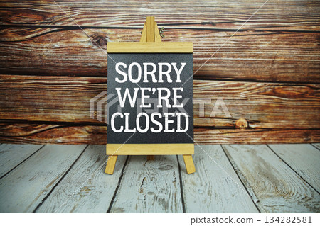 wooden easel holds a blackboard with the white text "Sorry We're Closed" set against a rustic wooden wall and light-colored wooden floor wooden easel holds a blackboard with the white text "Sorry We're Closed" set against a rustic wooden wall and light-colored wooden floor 134282581