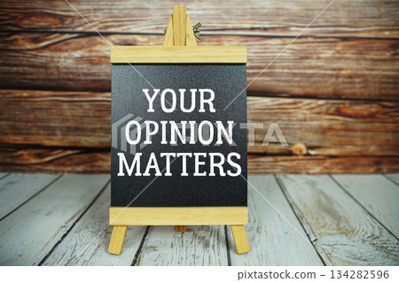 wooden easel holds a blackboard with the white text "Your Opinion Matters" set against a rustic wooden wall and light-colored wooden floor wooden easel holds a blackboard with the white text "Your Opinion Matters" set against a rustic wooden wall and light-colored wooden floor 134282596