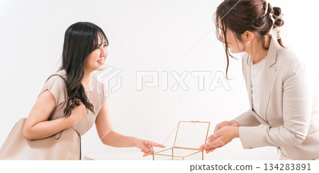 A woman choosing a wedding ring and a salesperson/staff at a jewelry store, accessory store, jewelry shop, or department store 134283891