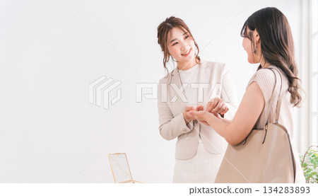 A woman choosing a wedding ring and a salesperson/staff at a jewelry store, accessory store, jewelry shop, or department store A woman choosing a wedding ring and a salesperson/staff at a jewelry store, accessory store, jewelry shop, or department store 134283893