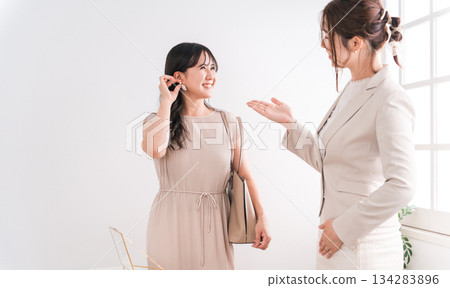 A woman choosing a wedding ring and a salesperson/staff at a jewelry store, accessory store, jewelry shop, or department store 134283896
