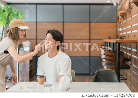 A female makeup artist putting makeup on a male model A female makeup artist putting makeup on a male model 134284708