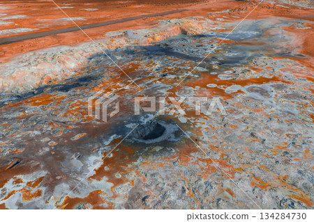 Geothermal landscape in Iceland featuring a bubbling mud pot, steaming ground, and vibrant orange and gray hues with barren volcanic terrain. Geothermal landscape in Iceland featuring a bubbling mud pot, steaming ground, and vibrant orange and gray hues with barren volcanic terrain. 134284730