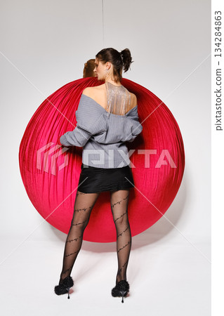Model poses with large red balloon in studio during fashion shoot 134284863